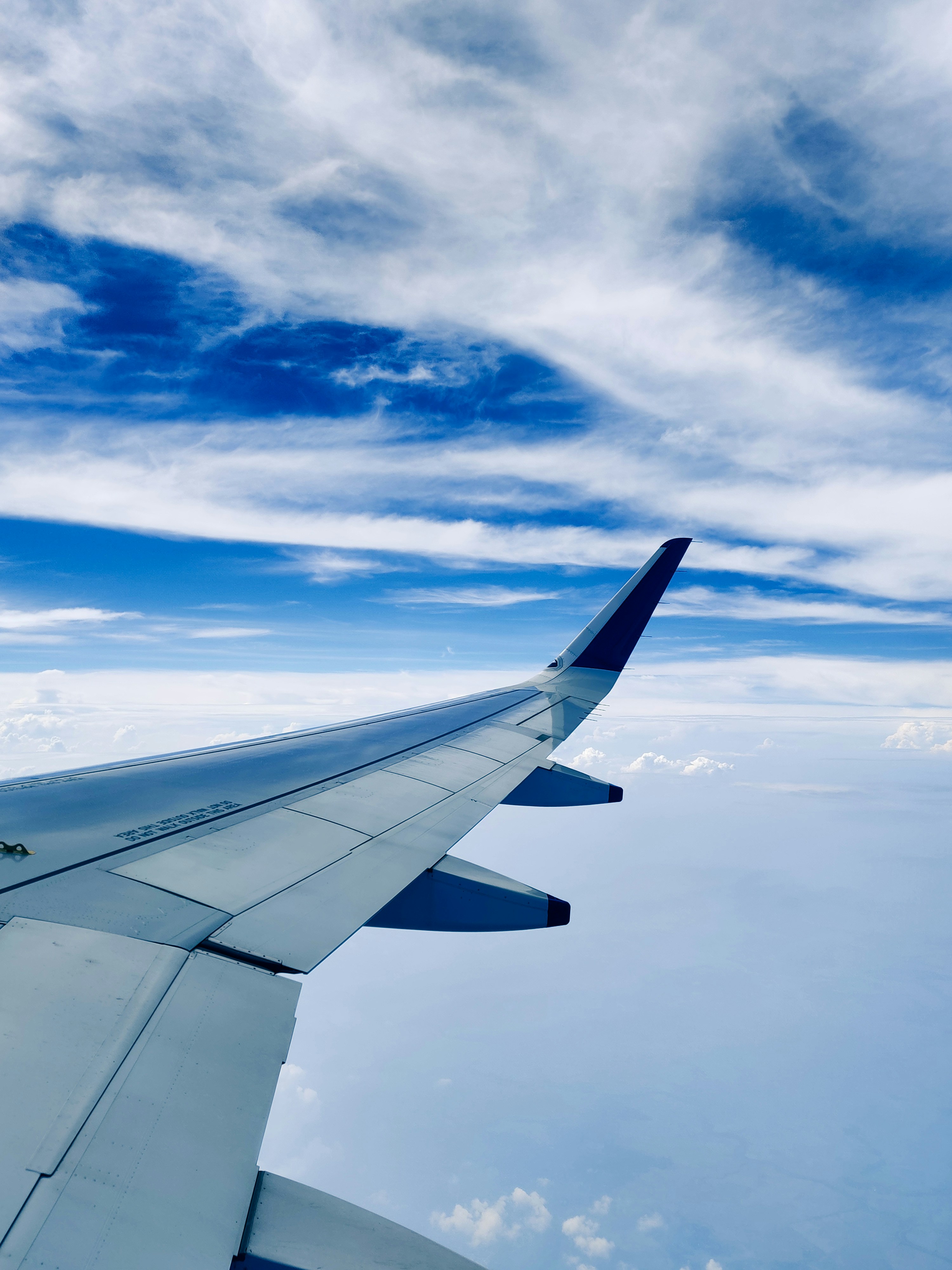 Airplane wing above clouds at sunrise — PleasantFlights